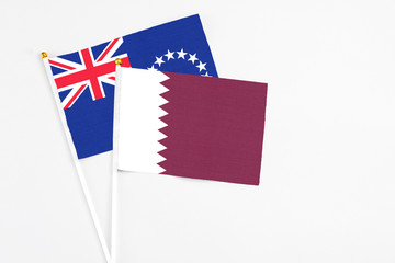 Qatar and Cook Islands stick flags on white background. High quality fabric, miniature national flag. Peaceful global concept.White floor for copy space.