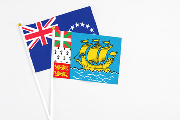 Saint Pierre And Miquelon and Cook Islands stick flags on white background. High quality fabric, miniature national flag. Peaceful global concept.White floor for copy space.