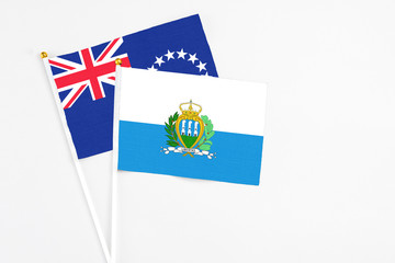 San Marino and Cook Islands stick flags on white background. High quality fabric, miniature national flag. Peaceful global concept.White floor for copy space.