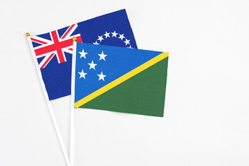Solomon Islands and Cook Islands stick flags on white background. High quality fabric, miniature national flag. Peaceful global concept.White floor for copy space.