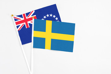 Sweden and Cook Islands stick flags on white background. High quality fabric, miniature national flag. Peaceful global concept.White floor for copy space.