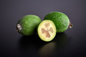 Green feijoa fruits on black concrete background table. Tropical fruit feijoa. Set of ripe feijoa fruits.