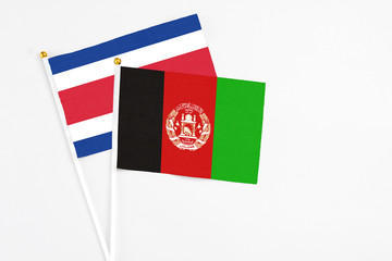 Afghanistan and Costa Rica stick flags on white background. High quality fabric, miniature national flag. Peaceful global concept.White floor for copy space.