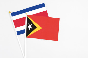 East Timor and Costa Rica stick flags on white background. High quality fabric, miniature national flag. Peaceful global concept.White floor for copy space.