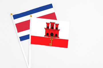 Gibraltar and Costa Rica stick flags on white background. High quality fabric, miniature national flag. Peaceful global concept.White floor for copy space.