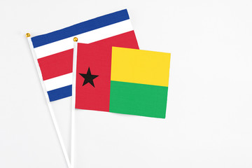 Guinea Bissau and Costa Rica stick flags on white background. High quality fabric, miniature national flag. Peaceful global concept.White floor for copy space.