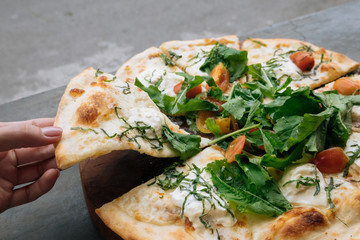 Female hand take a piece of Fresh italian pizza with tomatoes, cheese, basil on black stone table. Copy space. Homemade with love. Fast delivery. Recipe and menu. Top view.
