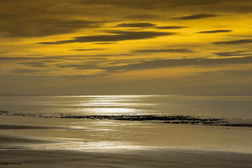 Fototapeta na wymiar Low sun on an autumn day on a beach at low tide
