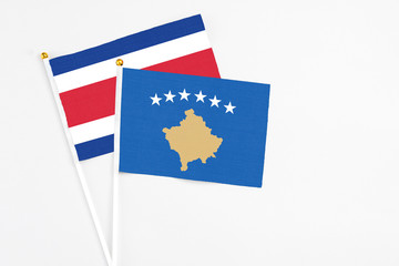 Kosovo and Costa Rica stick flags on white background. High quality fabric, miniature national flag. Peaceful global concept.White floor for copy space.