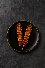 Chicken skewers on black plate