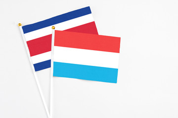 Luxembourg and Costa Rica stick flags on white background. High quality fabric, miniature national flag. Peaceful global concept.White floor for copy space.