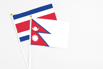 Nepal and Costa Rica stick flags on white background. High quality fabric, miniature national flag. Peaceful global concept.White floor for copy space.