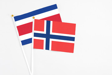 Norway and Costa Rica stick flags on white background. High quality fabric, miniature national flag. Peaceful global concept.White floor for copy space.