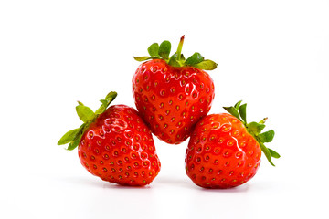 Close up of three ripe strawberries balancing on each other. All are isloated against a plain white background with space for copy