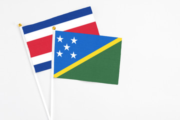 Solomon Islands and Costa Rica stick flags on white background. High quality fabric, miniature national flag. Peaceful global concept.White floor for copy space.