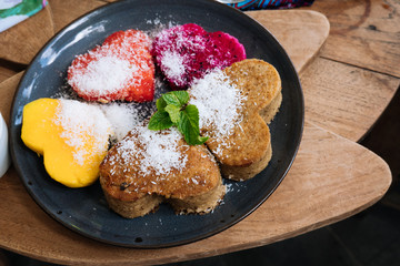 Oatmeal Pancakes and tropical fruits in the form of a heart with mint and honey on wooden table. Valentine's Day. Healthy food concept