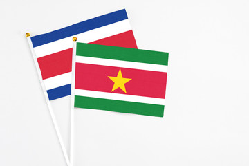 Suriname and Costa Rica stick flags on white background. High quality fabric, miniature national flag. Peaceful global concept.White floor for copy space.
