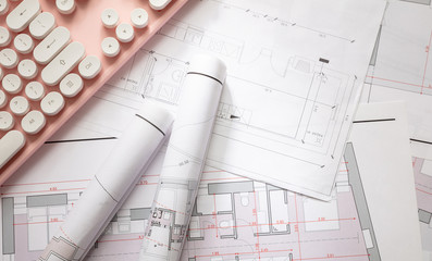 Construction concept. Residential building blueprint drawings and a pink computer keyboard