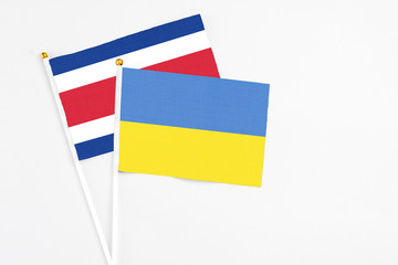 Ukraine and Costa Rica stick flags on white background. High quality fabric, miniature national flag. Peaceful global concept.White floor for copy space.