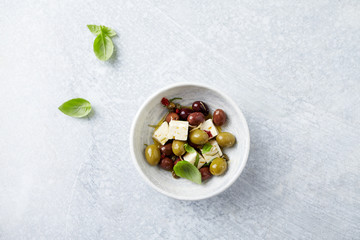 Green and Kalamata Olives, Capers and Feta Cheese on Bright Stone Background. Healthy Snack Idea. Top view. Copy space. 