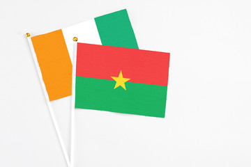 Burkina Faso and Cote D'Ivoire stick flags on white background. High quality fabric, miniature national flag. Peaceful global concept.White floor for copy space.