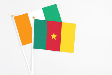 Cameroon and Cote D'Ivoire stick flags on white background. High quality fabric, miniature national flag. Peaceful global concept.White floor for copy space.