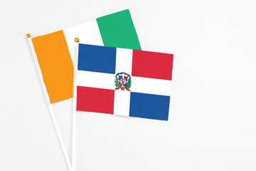 Dominican Republic and Cote D'Ivoire stick flags on white background. High quality fabric, miniature national flag. Peaceful global concept.White floor for copy space.