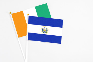 El Salvador and Cote D'Ivoire stick flags on white background. High quality fabric, miniature national flag. Peaceful global concept.White floor for copy space.