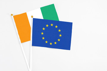 European Union and Cote D'Ivoire stick flags on white background. High quality fabric, miniature national flag. Peaceful global concept.White floor for copy space.