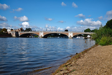 View of Hampton Court Bridge from the banks of the river Thames in Molesey, Surrey, on a sunny summer day