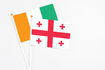 Georgia and Cote D'Ivoire stick flags on white background. High quality fabric, miniature national flag. Peaceful global concept.White floor for copy space.