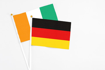 Germany and Cote D'Ivoire stick flags on white background. High quality fabric, miniature national flag. Peaceful global concept.White floor for copy space.