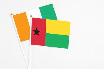 Guinea Bissau and Cote D'Ivoire stick flags on white background. High quality fabric, miniature national flag. Peaceful global concept.White floor for copy space.