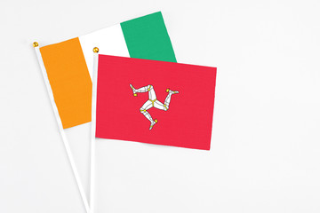 Isle Of Man and Cote D'Ivoire stick flags on white background. High quality fabric, miniature national flag. Peaceful global concept.White floor for copy space.
