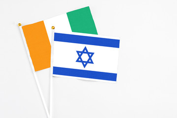 Israel and Cote D'Ivoire stick flags on white background. High quality fabric, miniature national flag. Peaceful global concept.White floor for copy space.