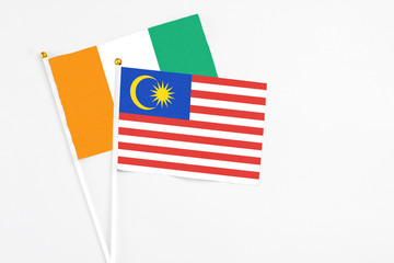 Malaysia and Cote D'Ivoire stick flags on white background. High quality fabric, miniature national flag. Peaceful global concept.White floor for copy space.