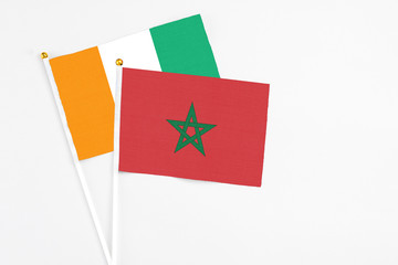 Morocco and Cote D'Ivoire stick flags on white background. High quality fabric, miniature national flag. Peaceful global concept.White floor for copy space.