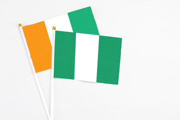 Nigeria and Cote D'Ivoire stick flags on white background. High quality fabric, miniature national flag. Peaceful global concept.White floor for copy space.