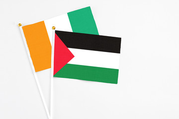 Palestine and Cote D'Ivoire stick flags on white background. High quality fabric, miniature national flag. Peaceful global concept.White floor for copy space.