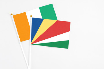 Seychelles and Cote D'Ivoire stick flags on white background. High quality fabric, miniature national flag. Peaceful global concept.White floor for copy space.