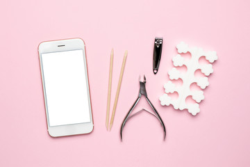 Mobile phone and manicure and pedicure tools on pink background