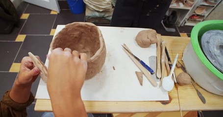 Sculptor modelling sculpture adjusting girl hand made of clay on wooden pottery table. 4K. Craft modern art in private studio. Training in modern artistic school, practice creative experience.