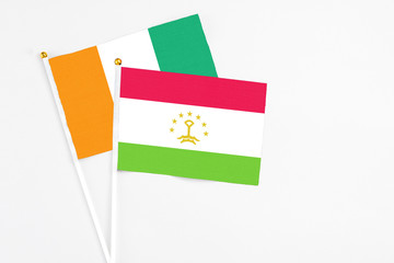 Tajikistan and Cote D'Ivoire stick flags on white background. High quality fabric, miniature national flag. Peaceful global concept.White floor for copy space.