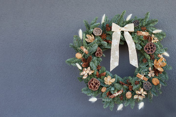 Christmas wreath made of natural fir branches  hanging on a grey wall.  Wreath with natural...