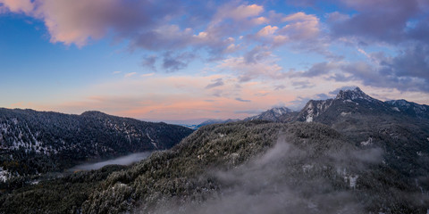 fairytale panorama of winter sunset sky in austrian mountains with snowy forest