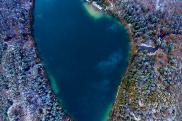 aerial view to blue lake Alatsee with snowy forest trees at winter