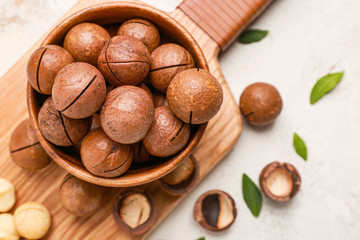 Bowl with macadamia nuts on white background