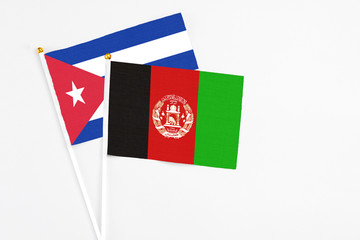 Afghanistan and Cuba stick flags on white background. High quality fabric, miniature national flag. Peaceful global concept.White floor for copy space.