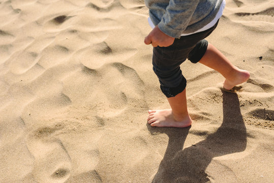 Feet of boy walking on the sand of the beach.