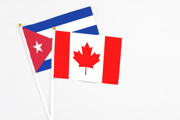 Canada and Cuba stick flags on white background. High quality fabric, miniature national flag. Peaceful global concept.White floor for copy space.